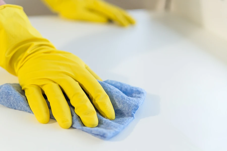 gloved hand wiping down a white surface