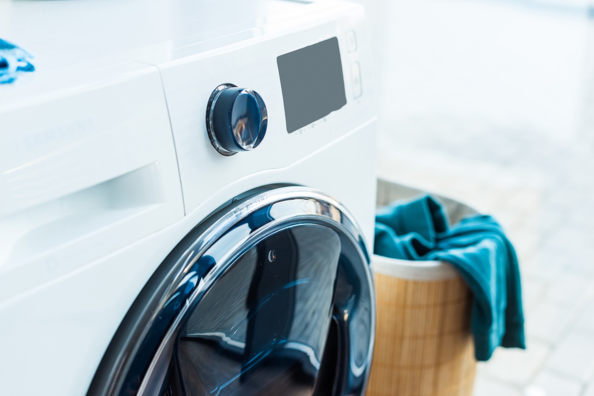 close-up view of modern washing machine and basket with laundry at home